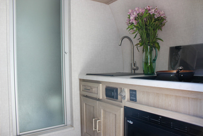  and a frosted glass door for a cozy travel space.|Compact RV rental kitchen featuring a sink — photo 32
