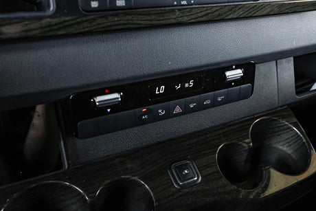 RV rental van's dashboard: Climate control panel displaying LO temperature and fan speed 5, with cup holders and wood trim.