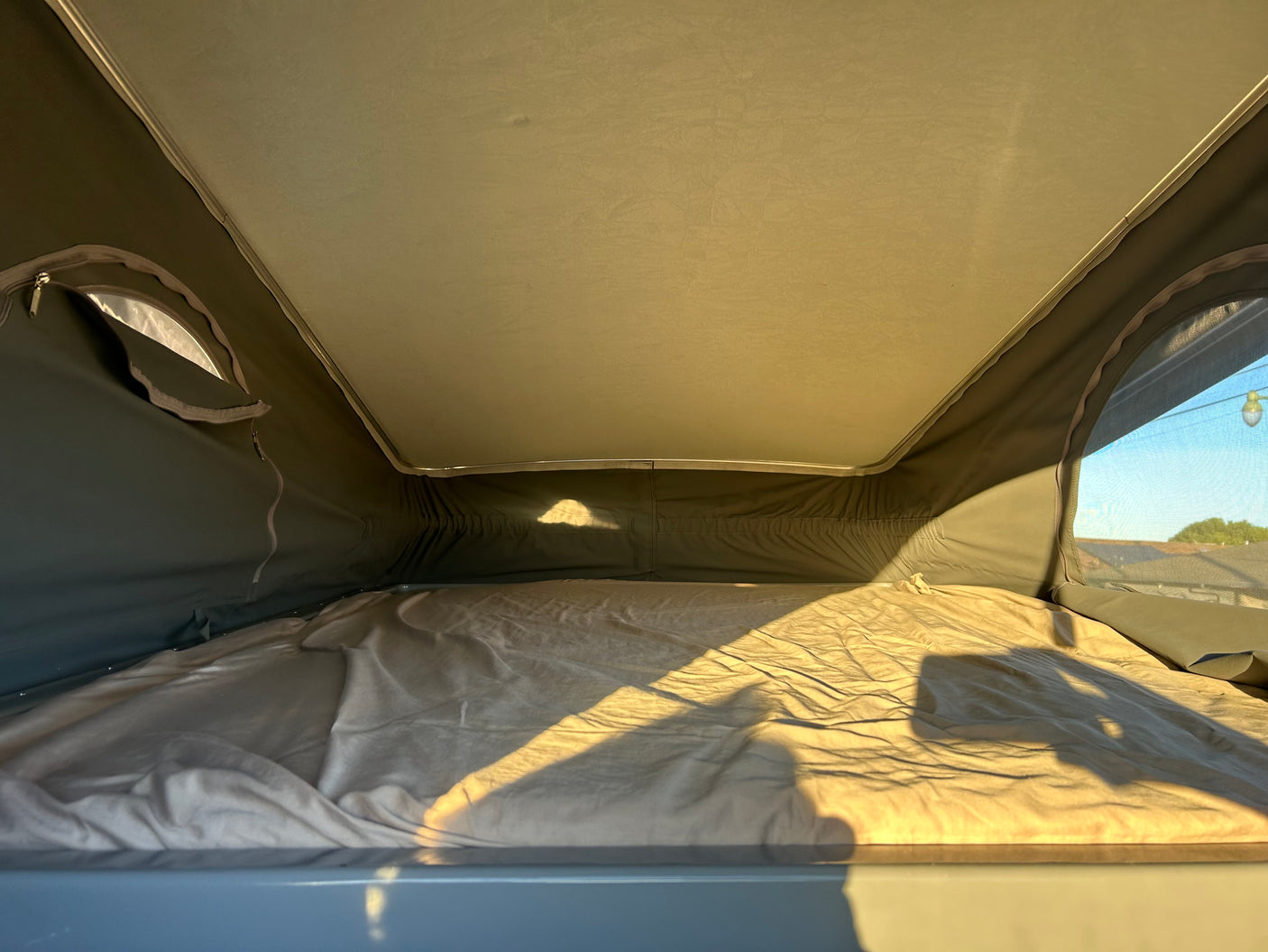 Cozy rv rental sleeping area inside a pop-top camper with sunlight illuminating the bed. Perfect for camping.