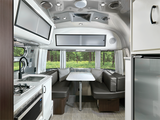 Modern Airstream-style RV interior with kitchen, dining area, and forest views. Ideal for your next rv rental.