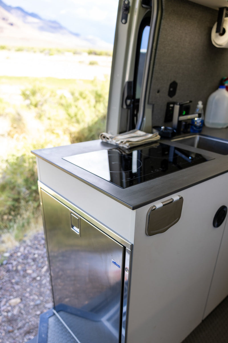  and cozy bed.|RV rental camper van parked in a lush forest with an open side door revealing a hanging chair. Ready for adventure.|Off-road RV rental van lighting up a misty redwood forest road — photo 3