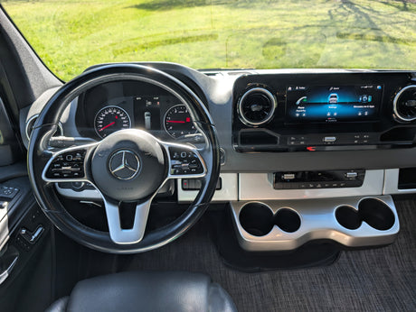 RV rental ready: Dashboard of a modern van featuring a steering wheel, digital instrument cluster, and large infotainment screen.
