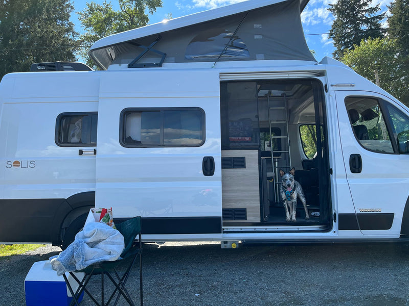  set up for a sunny outdoor day.|White Winnebago Solis pop-top RV rental with open door — photo 4