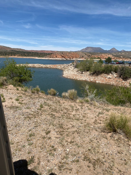 Blue lake nestled in arid hills with distant mountains & recreation area, ideal for RV rentals.