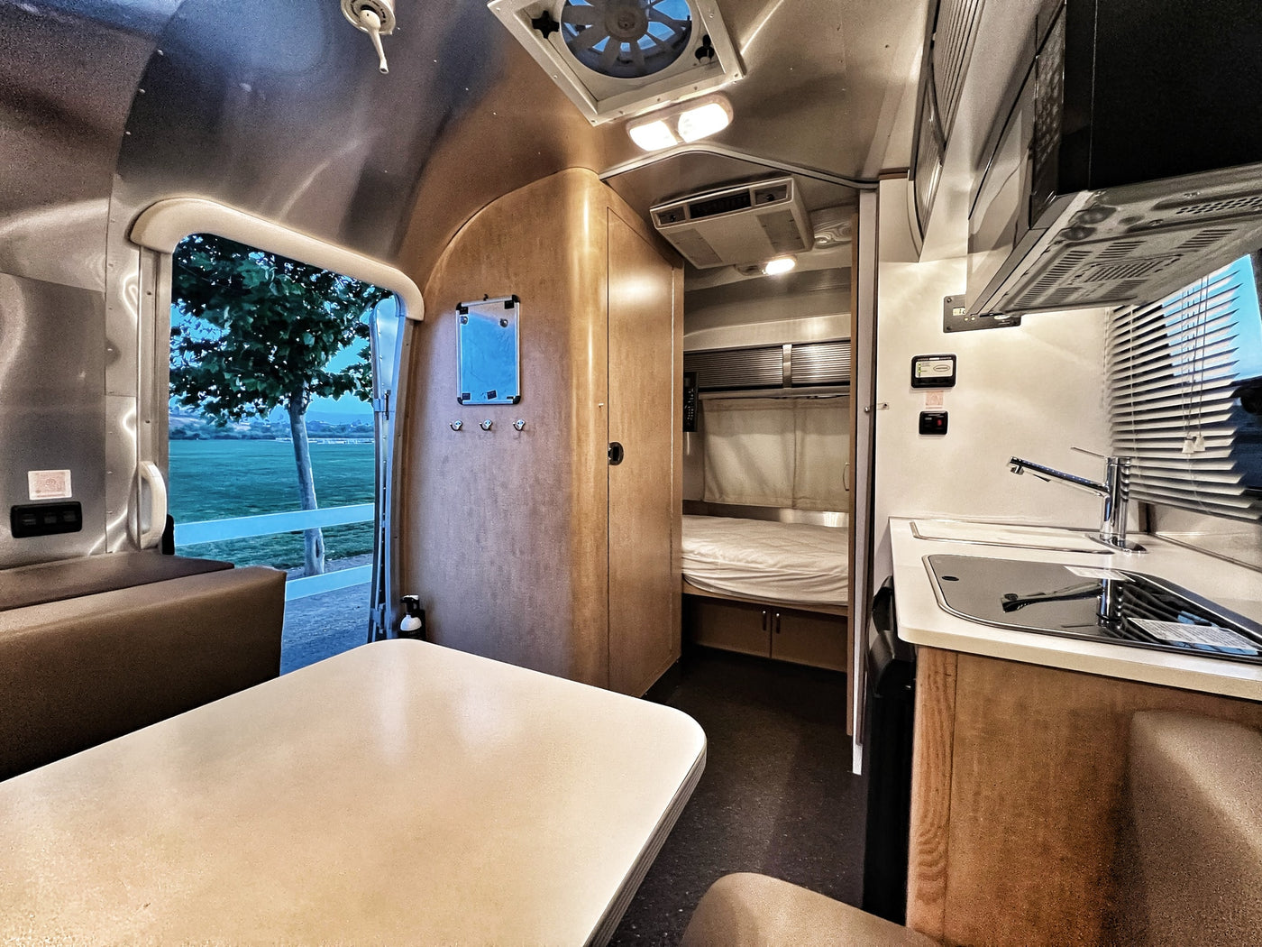 Experience comfort in this Airstream rv rental. Features a full kitchen, bedroom, and dining area with panoramic outdoor views. — photo 3