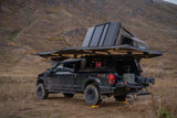 This rugged overlanding Ford F-150, equipped with a rooftop tent and lighted awning, offers the ultimate RV rental adventure in nature.