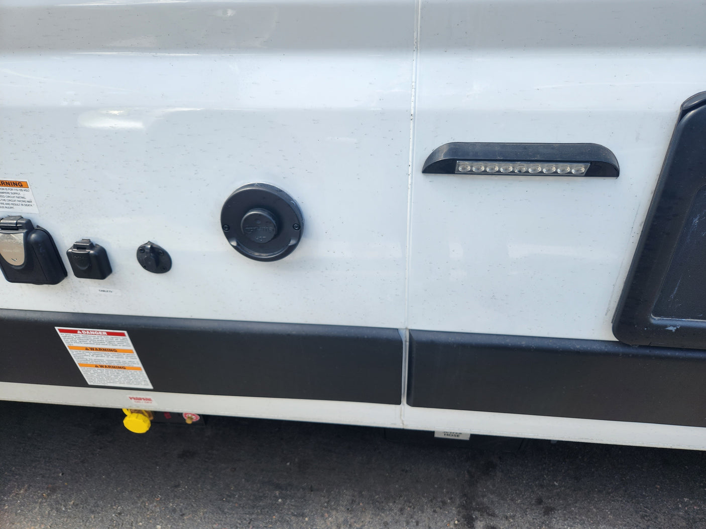 RV rental side panel with shore power, water, and propane hookups, plus an LED light strip.