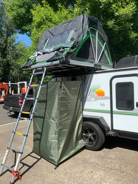 RV rental with a deployed roof-top tent, ladder, and privacy enclosure for camping adventures.