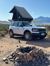A white Ford Bronco Sport with a rooftop tent at a desert campsite, ready for adventure. A rugged RV rental alternative!