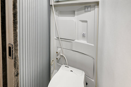 Clean, compact RV rental wet bath. Includes a Thetford toilet, shower, and switches for light & fan, with a ribbed sliding door.