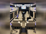 Luxurious RV rental interior: cream captain's chairs, large screen, and elegant ambient lighting.