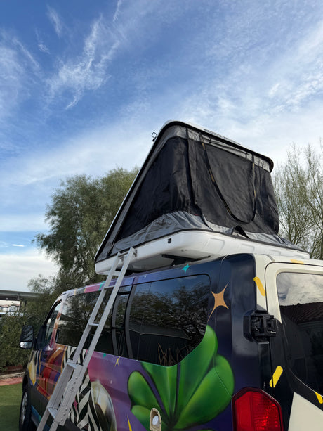 Colorful rv rental van featuring a deployed rooftop tent & ladder, perfect for van life adventures.