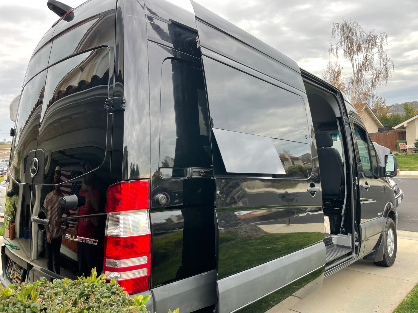 A shiny black Mercedes-Benz Sprinter van, an excellent RV rental option, is parked with its side door open. — photo 9