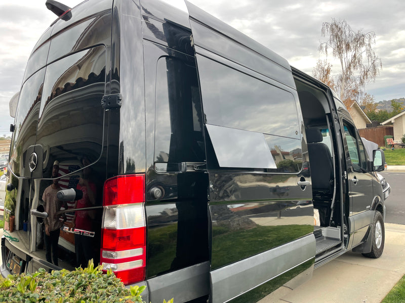 A shiny black Mercedes-Benz Sprinter van, an excellent RV rental option, is parked with its side door open. — photo 9