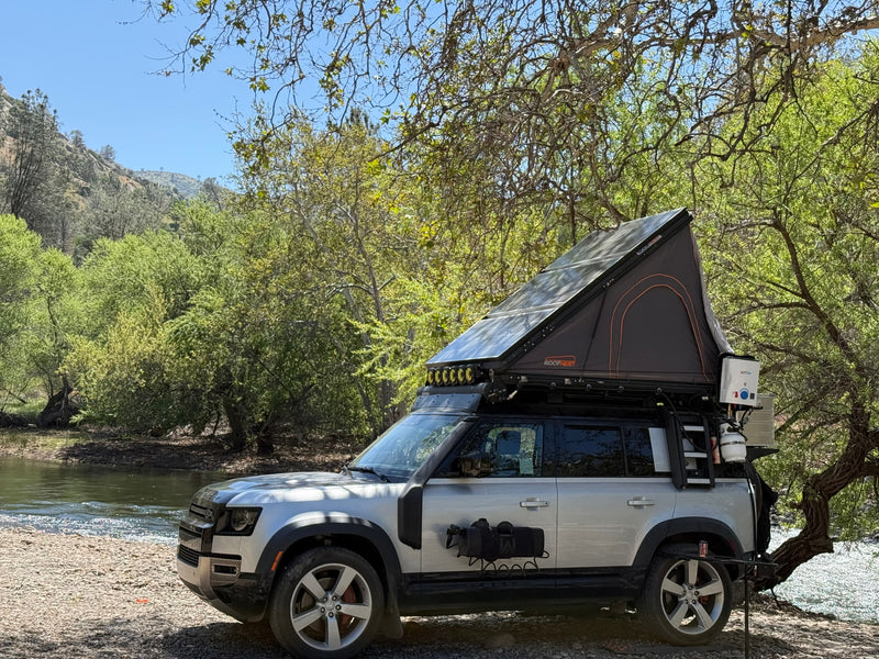 Custom Land Rover Defender w/ rooftop tent & gear by river. RV rental for overlanding adventures. — photo 11