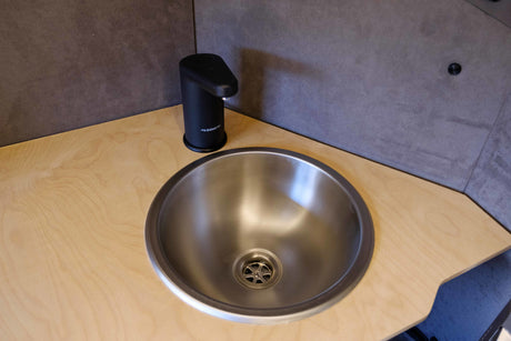 Compact stainless steel sink with Dometic faucet in an RV rental. Ideal for a campervan's utility space.