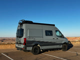 Exploring with an RV rental: a gray Winnebago Revel camper van parked at a scenic desert overlook.