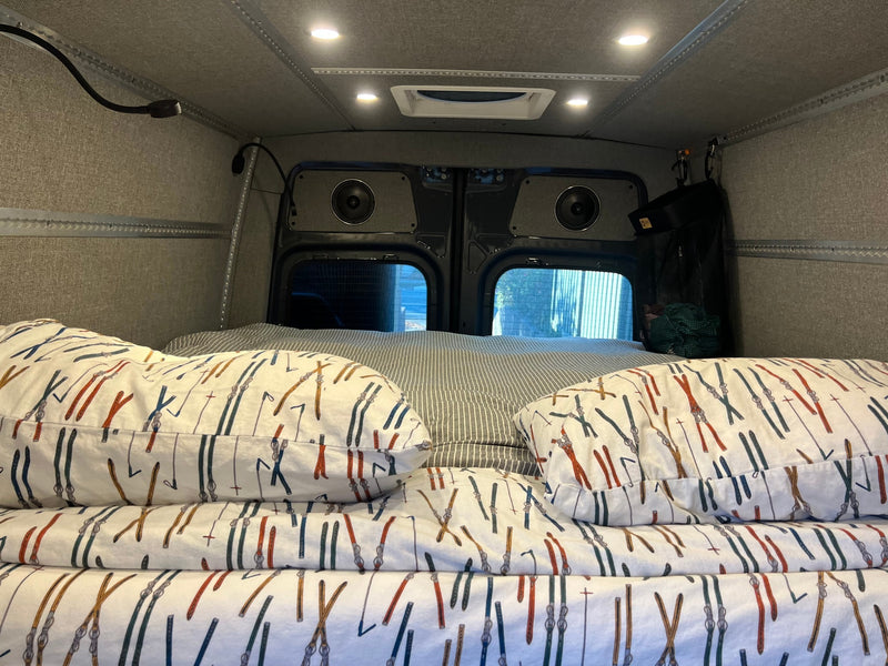 Cozy RV rental bed with ski-patterned bedding, built-in speakers, and ambient lighting, perfect for van life adventures. — photo 14