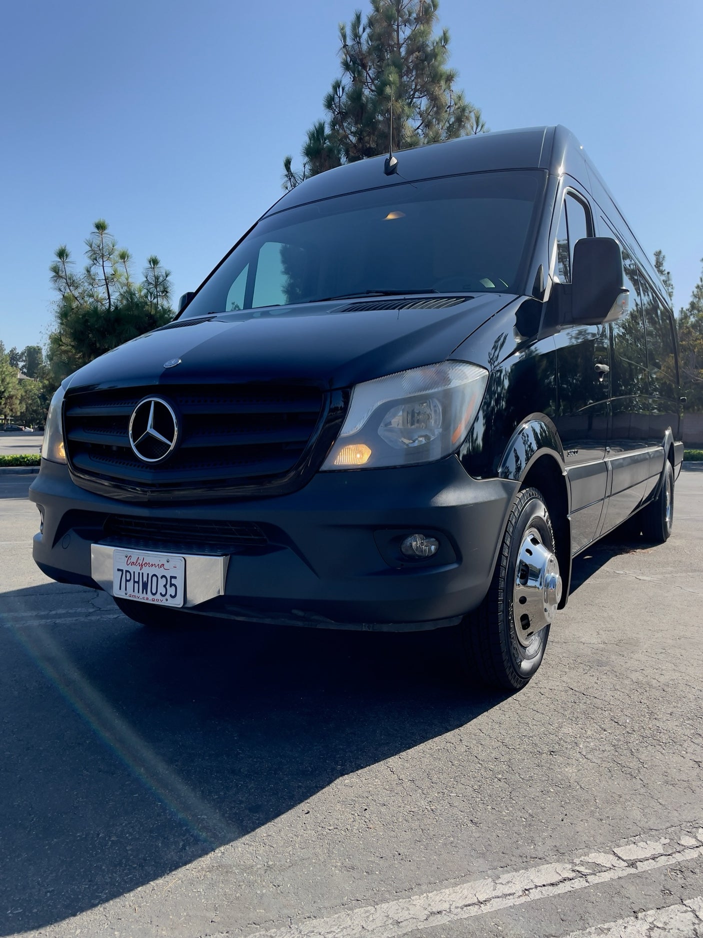 A sleek black Mercedes-Benz Sprinter van, great for RV rental. Parked outside with California plate 7PHW035 visible.