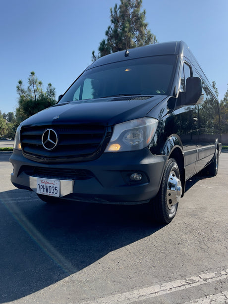 A sleek black Mercedes-Benz Sprinter van, great for RV rental. Parked outside with California plate 7PHW035 visible.