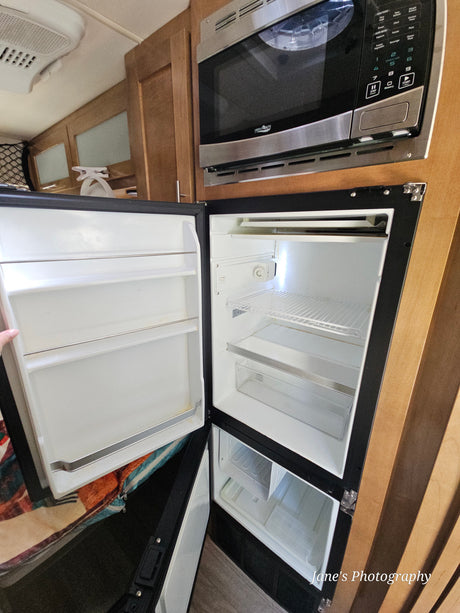**RV rental** kitchen showing an open, empty refrigerator and microwave oven, ready for use.