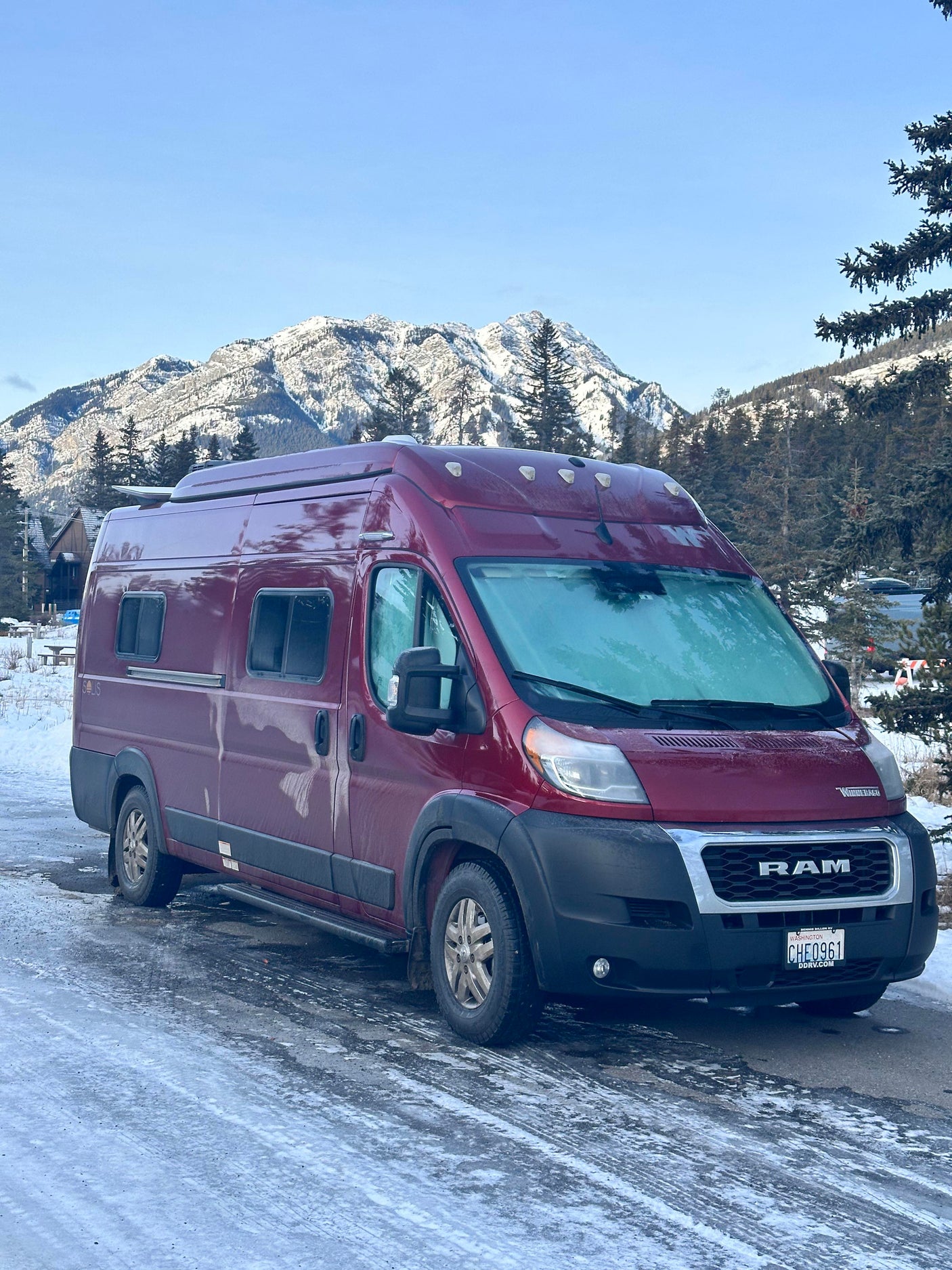 Red rv rental van, a Winnebago Solis, frosted up in snowy mountains. Perfect for winter adventures!