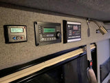 RV rental interior with control panels for heating, Xantrex inverter, and Camp Solar charge controller. Manage power for comfort.