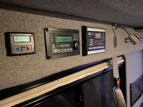 RV rental interior with control panels for heating, Xantrex inverter, and Camp Solar charge controller. Manage power for comfort.