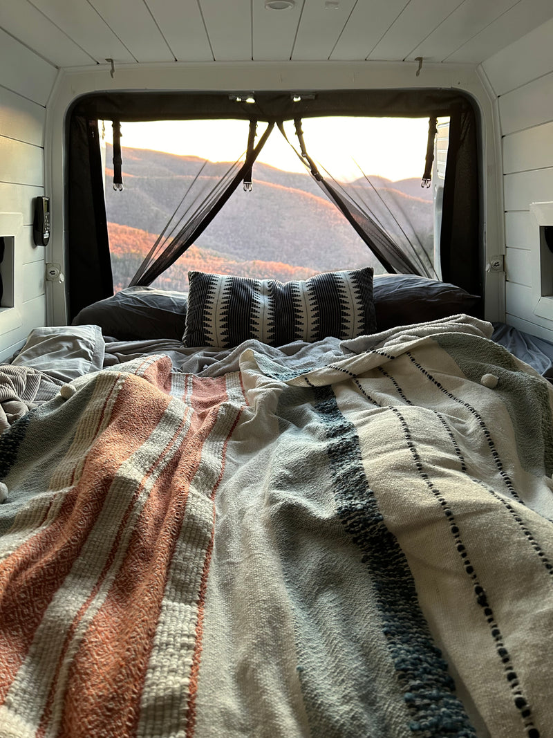 Cozy **rv rental** bed with mountain sunset views through a mesh screen, ideal for van life adventures. — photo 7