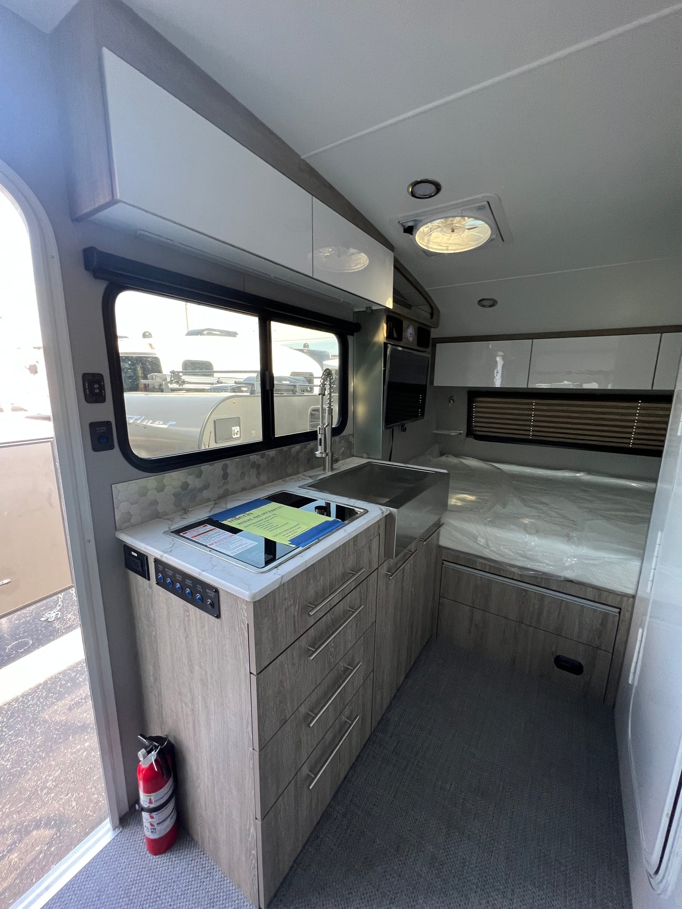 This rv rental's interior boasts a sleek kitchenette with cooktop and sink, ample storage, and a cozy bed.