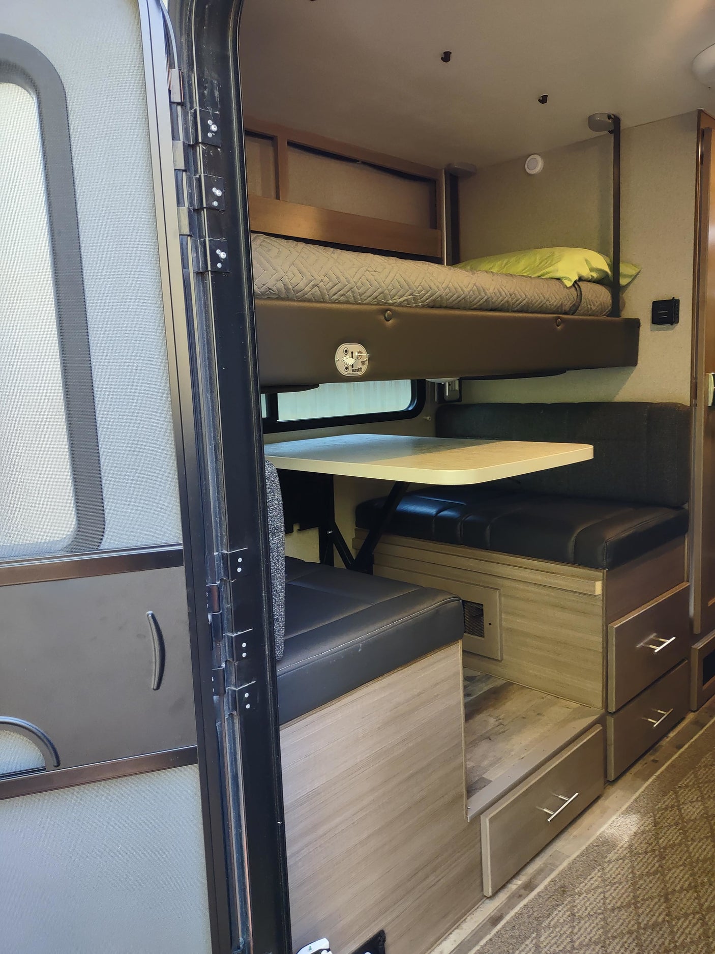 RV rental interior: bunk bed over a dinette with storage drawers. A functional and cozy space for travel.