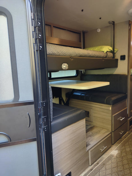 RV rental interior: bunk bed over a dinette with storage drawers. A functional and cozy space for travel.