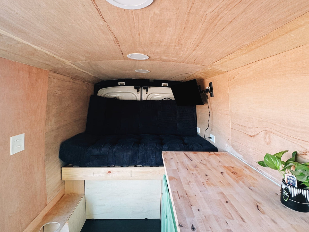  and wooden countertops for mobile living.|Cozy camper van interior with a bed — photo 6