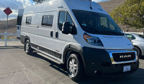 A white Winnebago camper van, built on a Ram ProMaster chassis, ideal for RV rental, parked outdoors on a sunny day.
