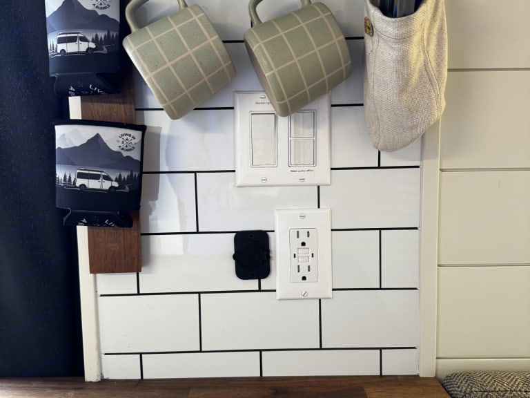 RV rental interior with modern subway tile backsplash, essential outlets, light switches, and creative hanging storage.