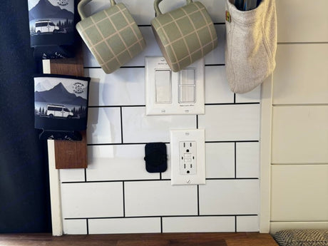 RV rental interior with modern subway tile backsplash, essential outlets, light switches, and creative hanging storage.