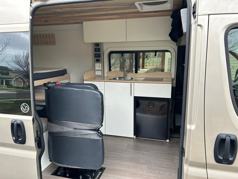Explore this RV rental's camper van interior: a cozy bed, full kitchen, and flexible seating for adventures. — photo 4