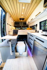 Modern RV rental interior: compact kitchen, cozy bed, & pull-out toilet. Smart design maximizes space in this camper van.