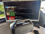 Inside an RV rental, a monitor displays Prime Video movies like Home Alone, alongside an Anker speaker, Xbox controller, and mouse for entertainment.