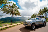 Experience a Hawaiian adventure with this RV rental! Silver Tacoma with rooftop tent overlooks lush mountains & taro fields.