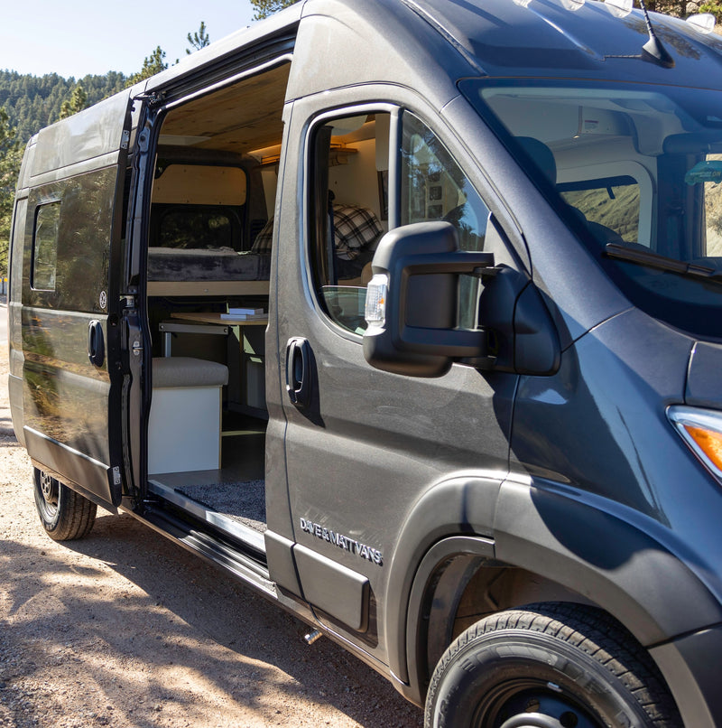 This inviting RV rental camper van, with its side door open, reveals a cozy, custom interior perfect for adventure travel. — photo 4