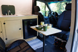 RV rental camper van interior featuring a compact kitchen, small dining table, and swiveling front seats.