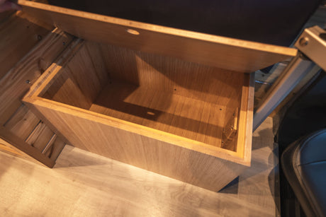 An open wooden storage box is featured within an RV rental, showcasing practical interior organization.