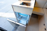 RV rental kitchen: open compact fridge, induction cooktop, and custom wood cabinetry. Perfect for road trips.