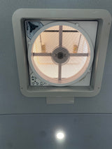 Overhead MaxxFan ceiling vent in an rv rental interior, showing its screen, controls, and a recessed ceiling light.
