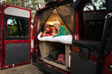 Couple enjoys their RV rental camper van bed amidst nature. Perfect for outdoor adventure & travel.
