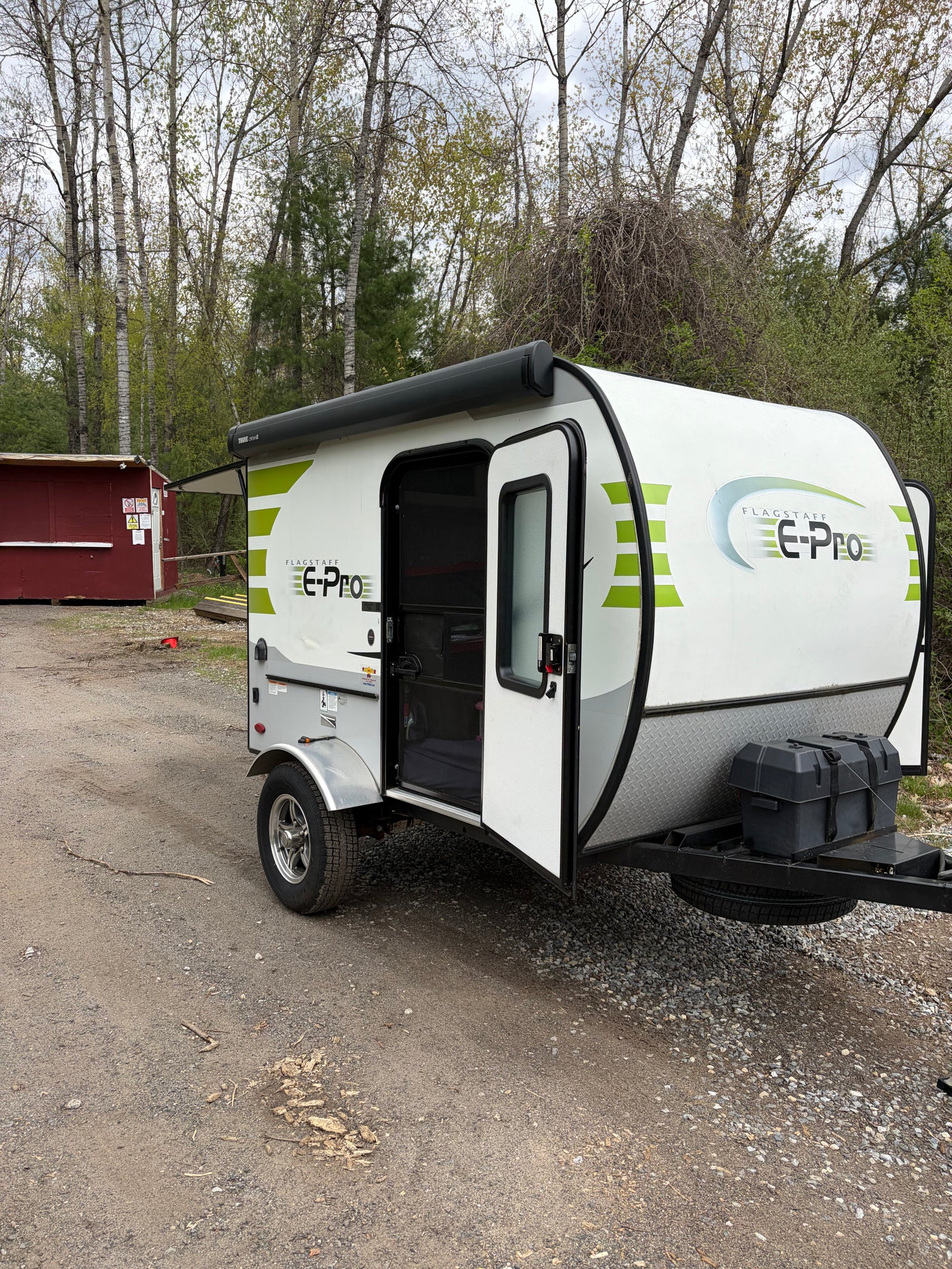 RV rental: A white and green Flagstaff E-Pro travel trailer with its door open, parked on a gravel lot.