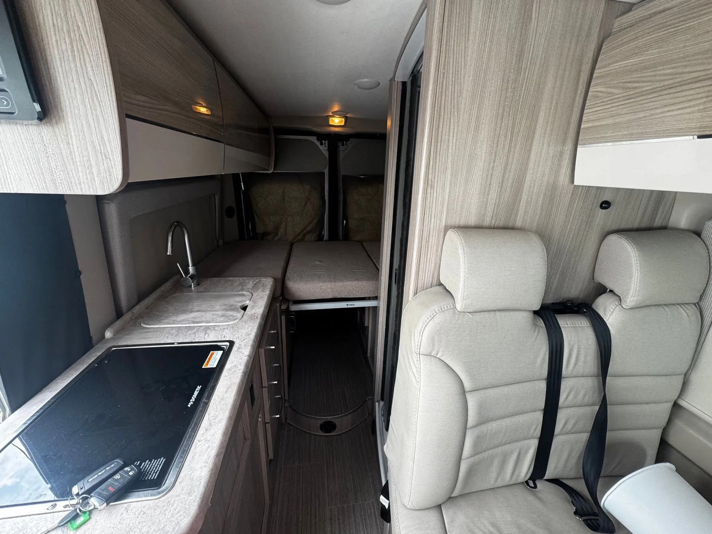 Explore the cozy interior of an rv rental: a kitchenette, convertible bed, and passenger seating ready for your next road trip. — photo 7