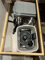 RV rental kitchen storage: compact pots, pans, and toaster neatly organized in a drawer for camping cooking.