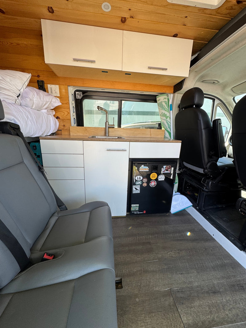  and hitch. Great for rv rental!|Side view of a white camper van RV rental with a tinted window and roof rack system.|RV rental interior featuring grey passenger seating — photo 4